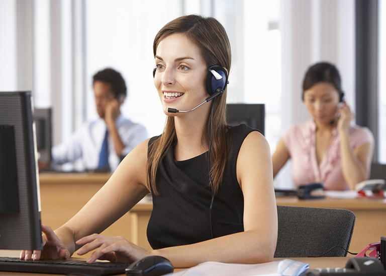 Junge Dame in Kleid mit Headset am PC