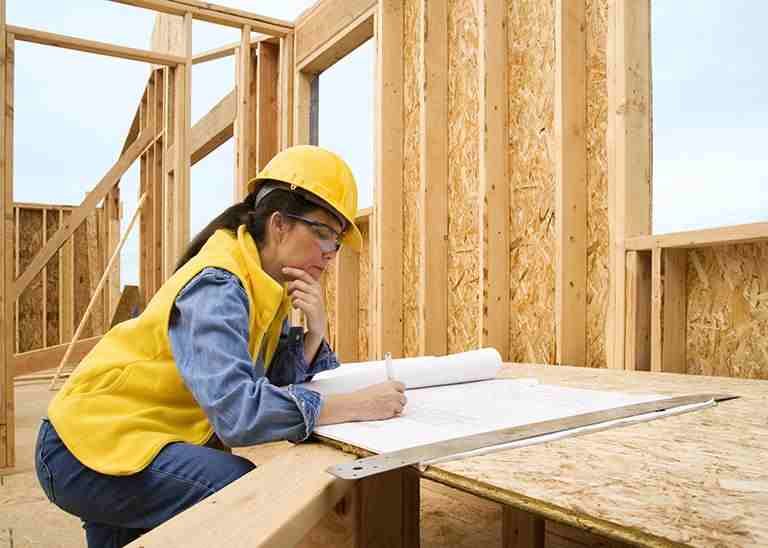 Frau mit Helm auf Holzhaus Baustelle mit Plan