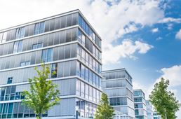 Modernes Bürogebäude in Stadt mit Himmel und Wolken