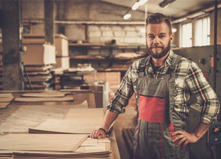 Handwerker mit Schürze vor Werkbank in Werkstatt