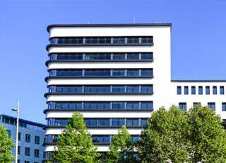 Großes Bürogebäude mit Bäumen und blauem Himmel